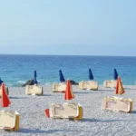 a bunch of chairs and umbrellas on a beach