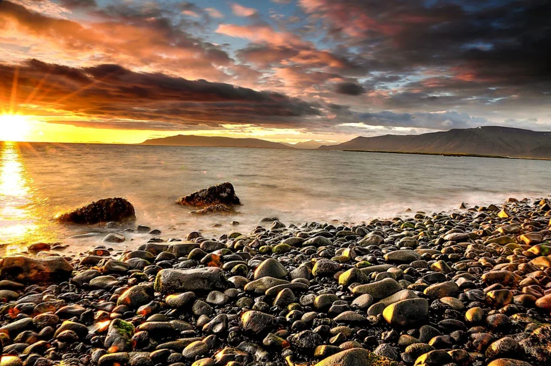 The sun is setting over a rocky beach