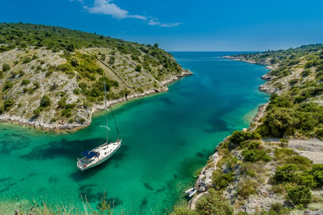 aerial photography of white boat near body of water between green mountain during daytime